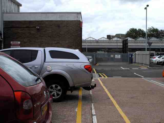 A pedestrian strip with obstructing vehicle and risk of reversing into children, invisible in rear view mirror. The building on the left is a childrens' 'soft play' attraction.